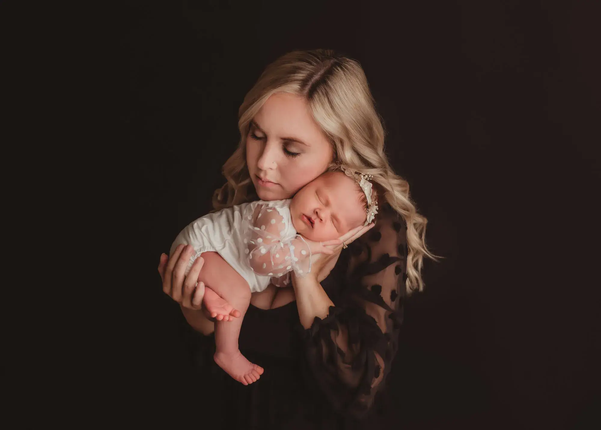 A sleeping newborn held close in a studio portrait